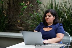 Woman engineer working on code on a patio with plants 49Rxab