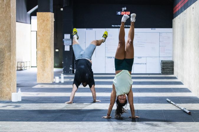 Strong athletes doing hand stand in gym