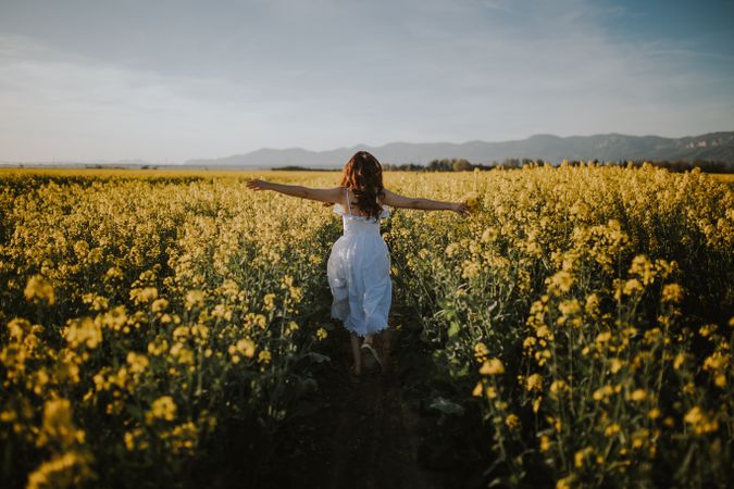 Anonymous woman walking in flower field