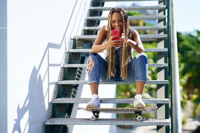Female skater texting on phone on stairs, copy space