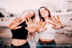 Two young women holding their hands in the foreground showing traces of gold glitter A0yxab