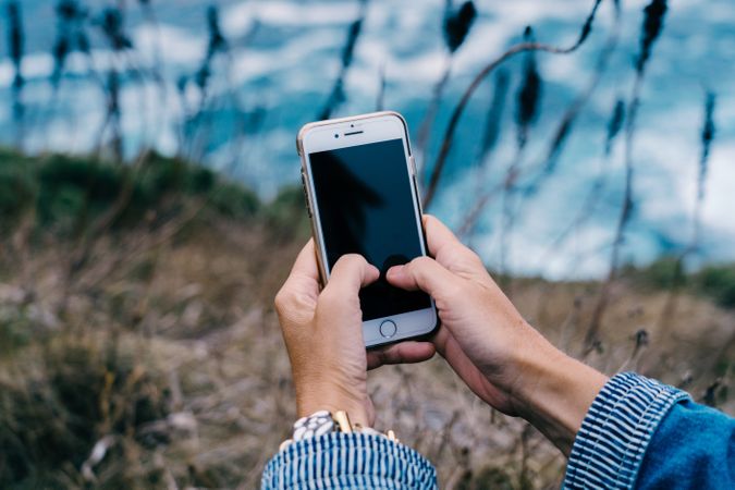 Person using smartphone while chilling at coast