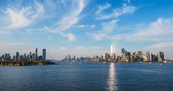 Aerial Photo with Manhattan Island with Office and Apartment Buildings. Hudson River Scenery with Yachts, Boats, and Sun Reflecting From the One World Trade Center Skyscraper