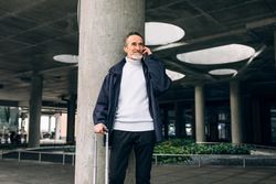 Stylish mature tourist taking phone call outdoors