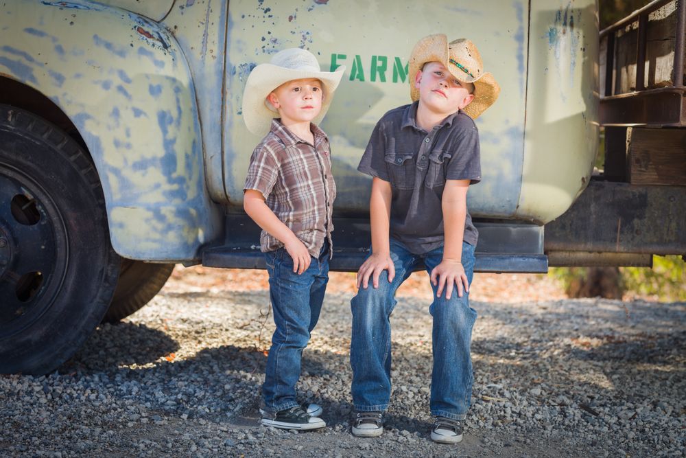Young Boys Wearing Cowboy Hats Leaning Against an Antique Truck