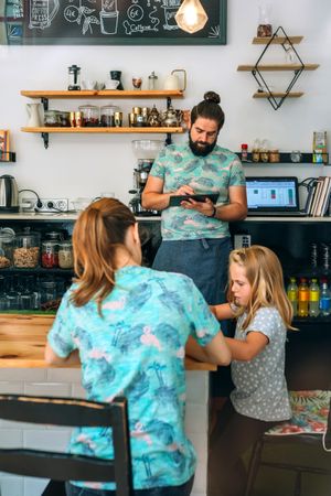Mother drawing with her daughter while father works in their own coffee shop
