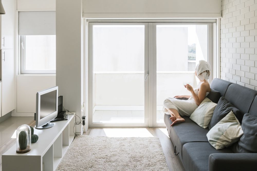 Adult relaxed woman enjoying life while resting on sofa and having hot drink after shower in own cozy apartment