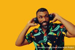 Smiling Black male in bold patterned shirt and headphones in yellow room 5kAxAb