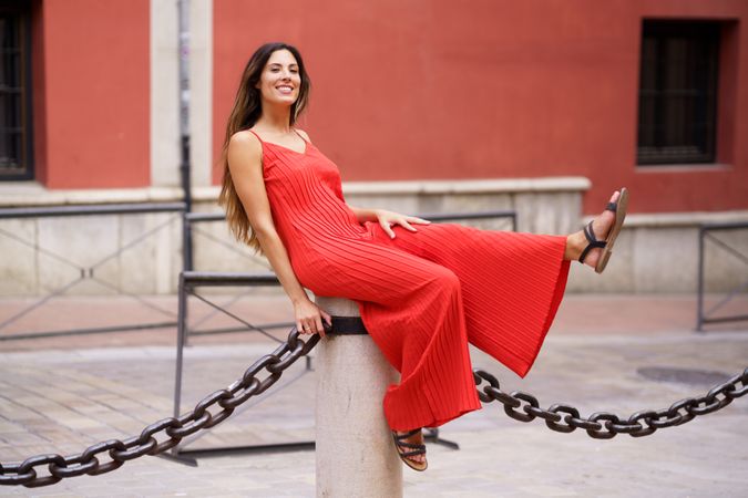 An Enchanting and Charming Woman Dressed Elegantly in a Red Dress Posing Playfully Outdoors