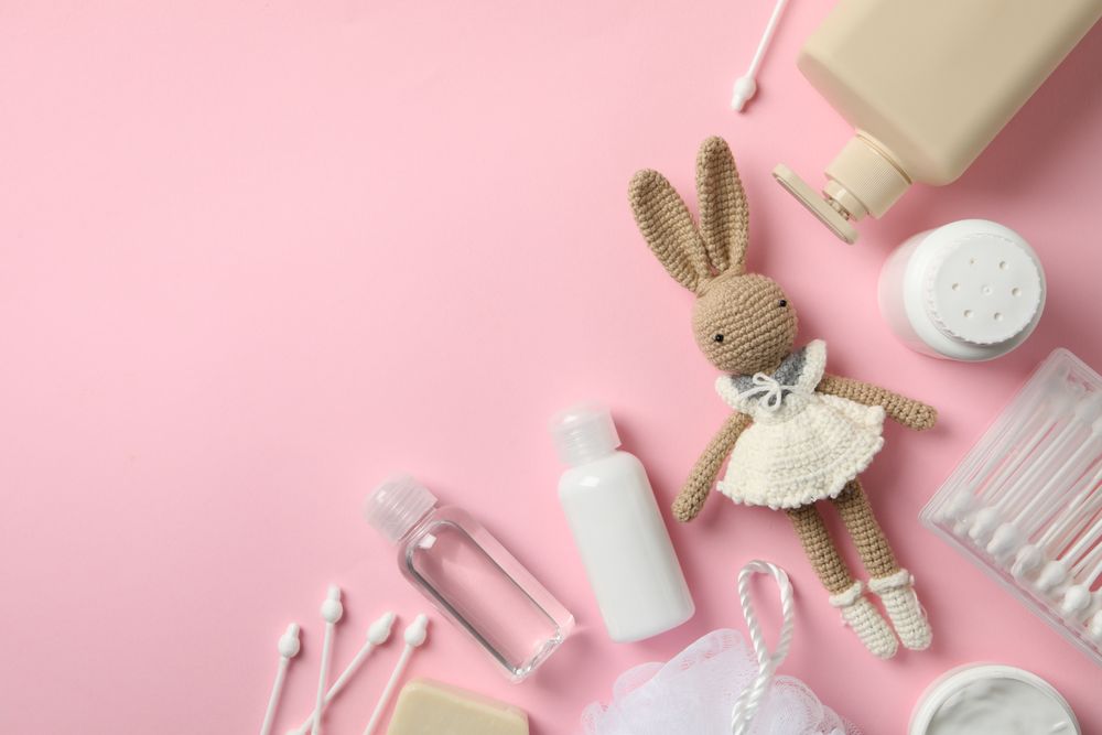 Baby hygiene accessories on pink background, top view