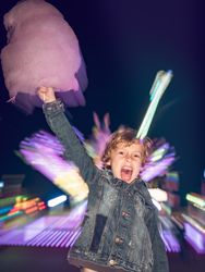 Excited boy with cotton candy near attraction
