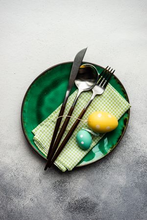 Easter table setting with green plate and colorful egg ornaments