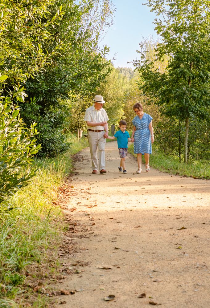 Grandparents and grandchild walking outdoors, vertical