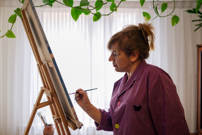 Adult woman painting canvas at home