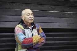 Pensive mature man with arms folded against house