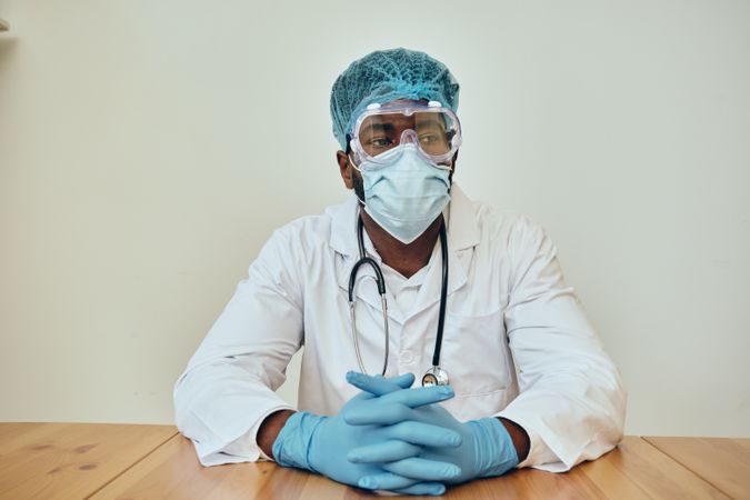 Black male doctor in ppe gear at a table in the hospital break room
