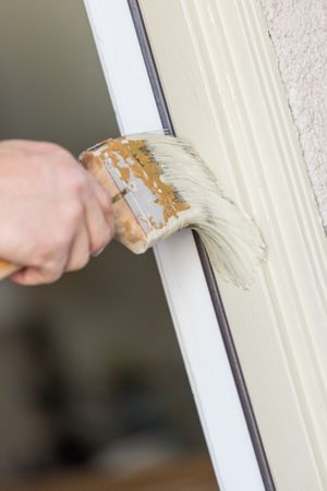 Professional Painter Cutting In With Brush to Paint House Door Frame.