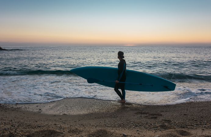 Man practicing paddle surfing with neoprene in a sunrise