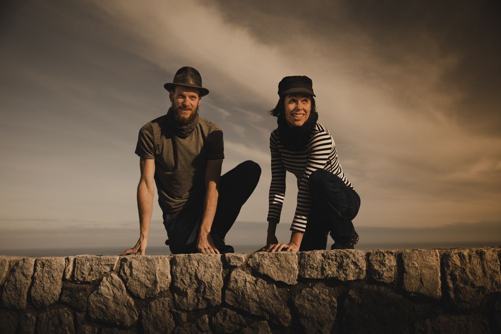 Man and woman leaning out from stones