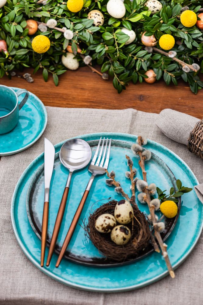 Table setting for Easter holiday dinner with speckled eggs in nest