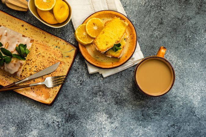 Top view of tasty lemon cake with fresh mint served on orange plates with tea, with space for text