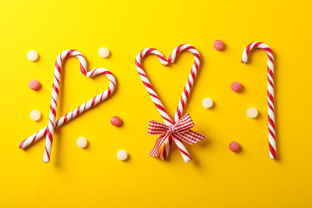 Flat lay composition with candy canes on yellow background, space for text