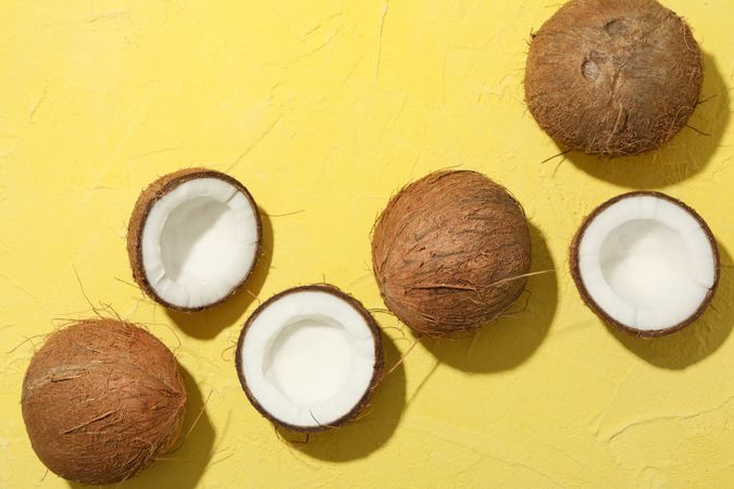 Coconut on yellow background, top view. Tropical fruit