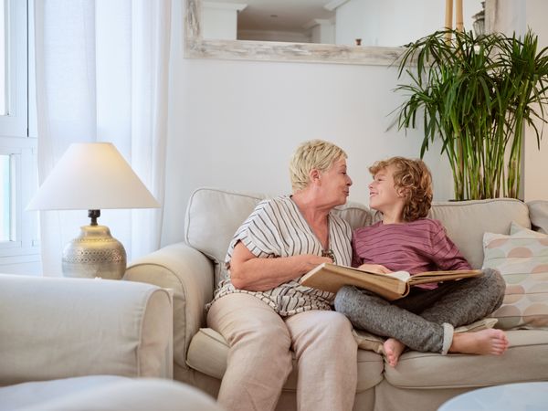 Grandmother and grandson reading book in room