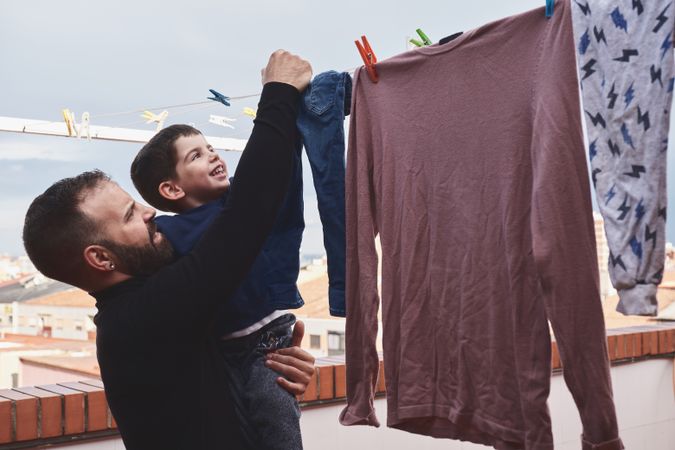 Father and son hanging clothes on rope