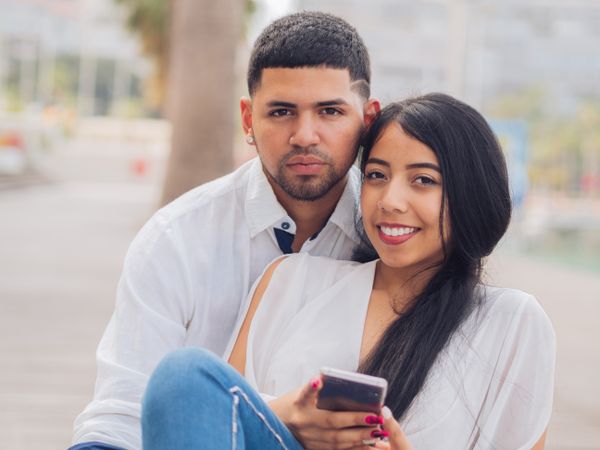 Man bonging smiling woman having fun with smartphone