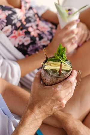 Crop couple drinking cocktails together