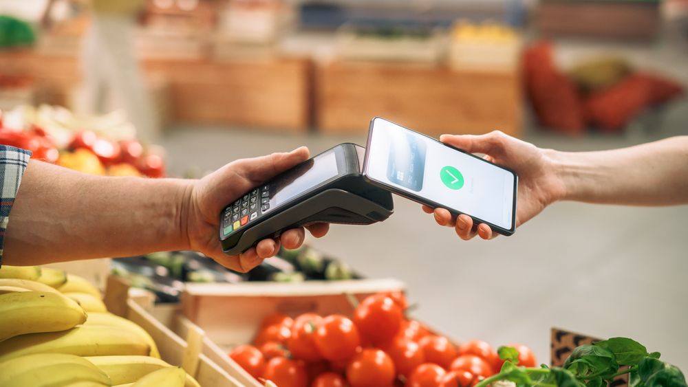 Close Up of a Customer Making a Secure Contactless Online Payment Using a Smartphone with a Credit Card Banking NFC App.