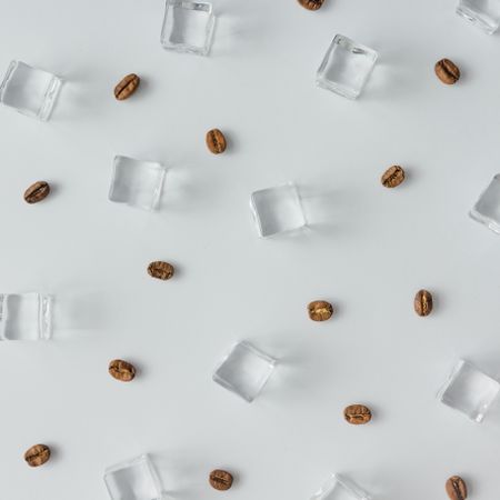 Coffee beans and ice cubes pattern on bright background