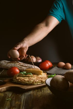 Crop man holding eggs near pie