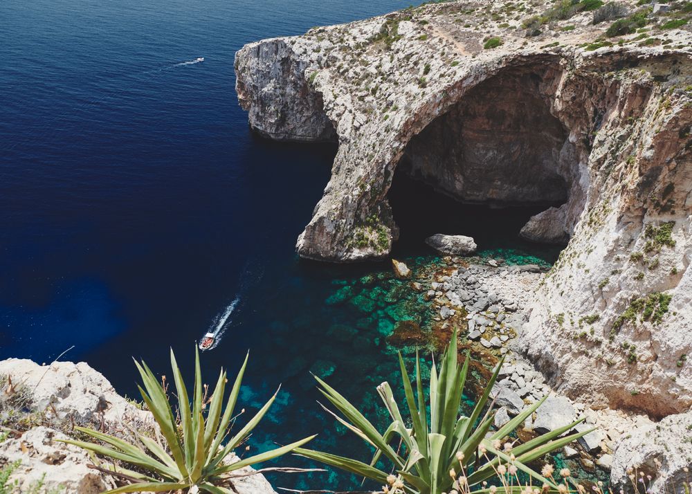 Boats speeding around eroded cliffs in Malta