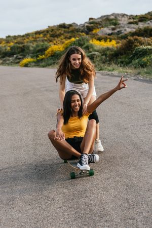 Happy diverse women riding longboard on road