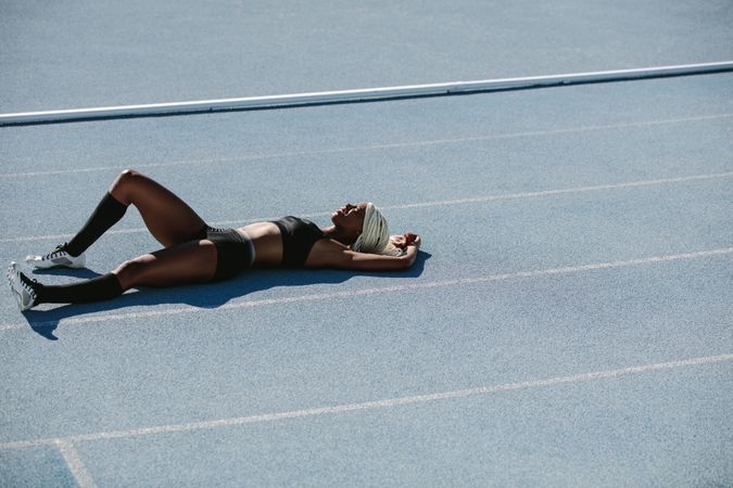 Woman athlete lying on the running track relaxing after training