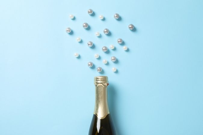 Champagne bottle and glitter on blue background, space for text