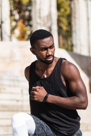 Black sportsman stretching on basketball court