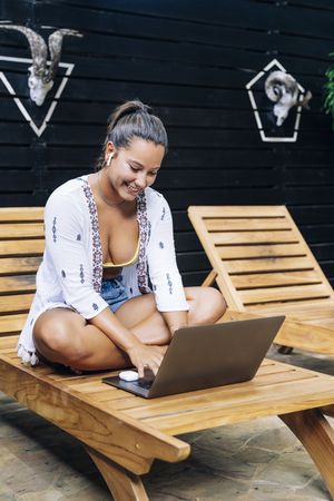Relaxed woman using laptop while resting on deck chair
