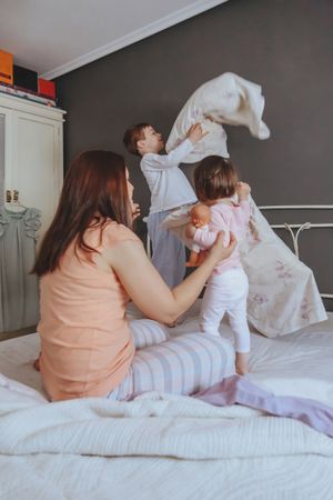 Portrait of happy woman and two children playing in bed on a relaxed morning