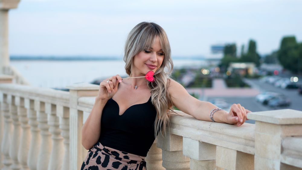 Beautiful young woman with red heart shaped lollipop