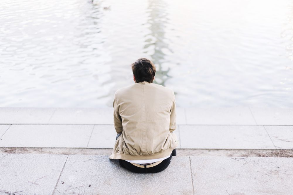 Man sitting looking out at lake on a peaceful day