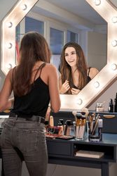 Happy young woman standing near visage table