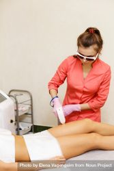 Woman having hair removed on thigh with laser treatment, vertical bxxjZb