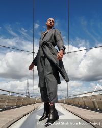 Stylish young man in gray coat and pants on bridge 0WVMOb