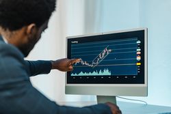 Black man analyzing financial diagrams on binary option