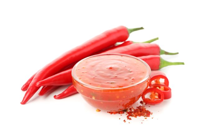 Chilli pepper and bowl of sauce isolated on plain background