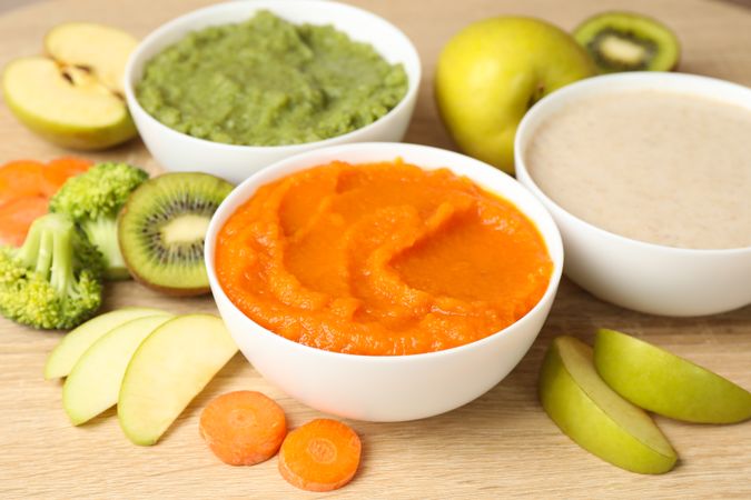 Bowls with vegetable puree on wooden background. Baby food