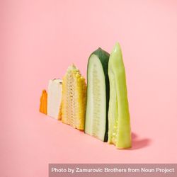 Various vegetables sliced in half showing cross-section on pastel pink background bEWR15